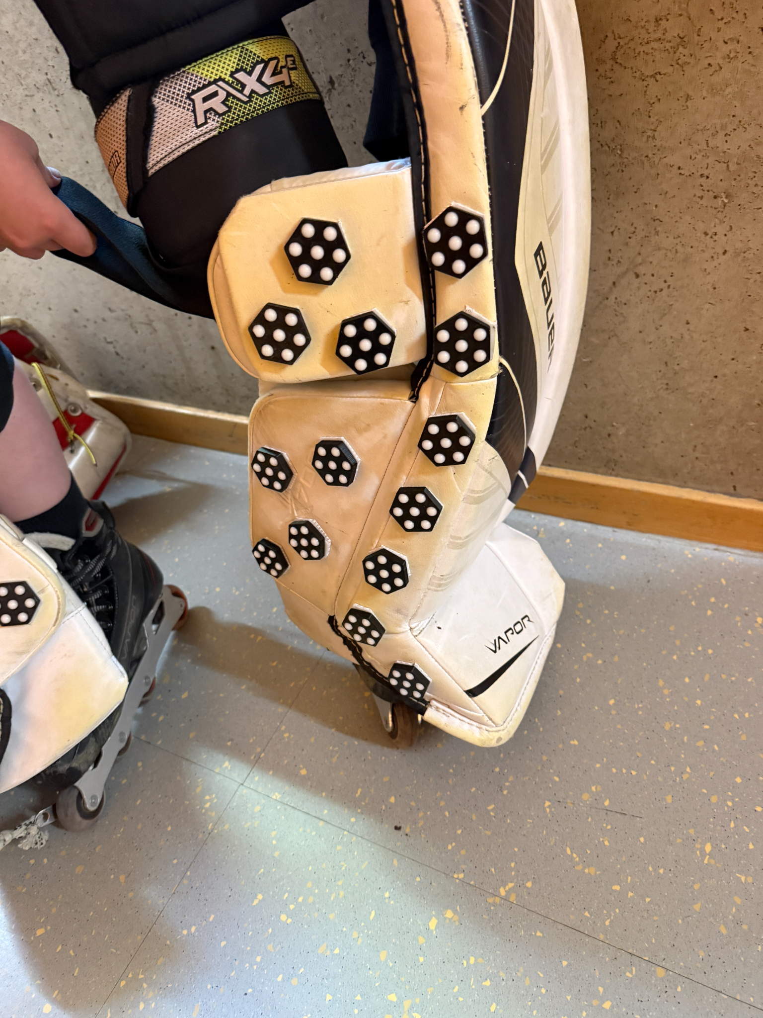 Nahaufnahme von mehreren Slidofix-Elementen auf einem weißen Goalie-Beinschoner